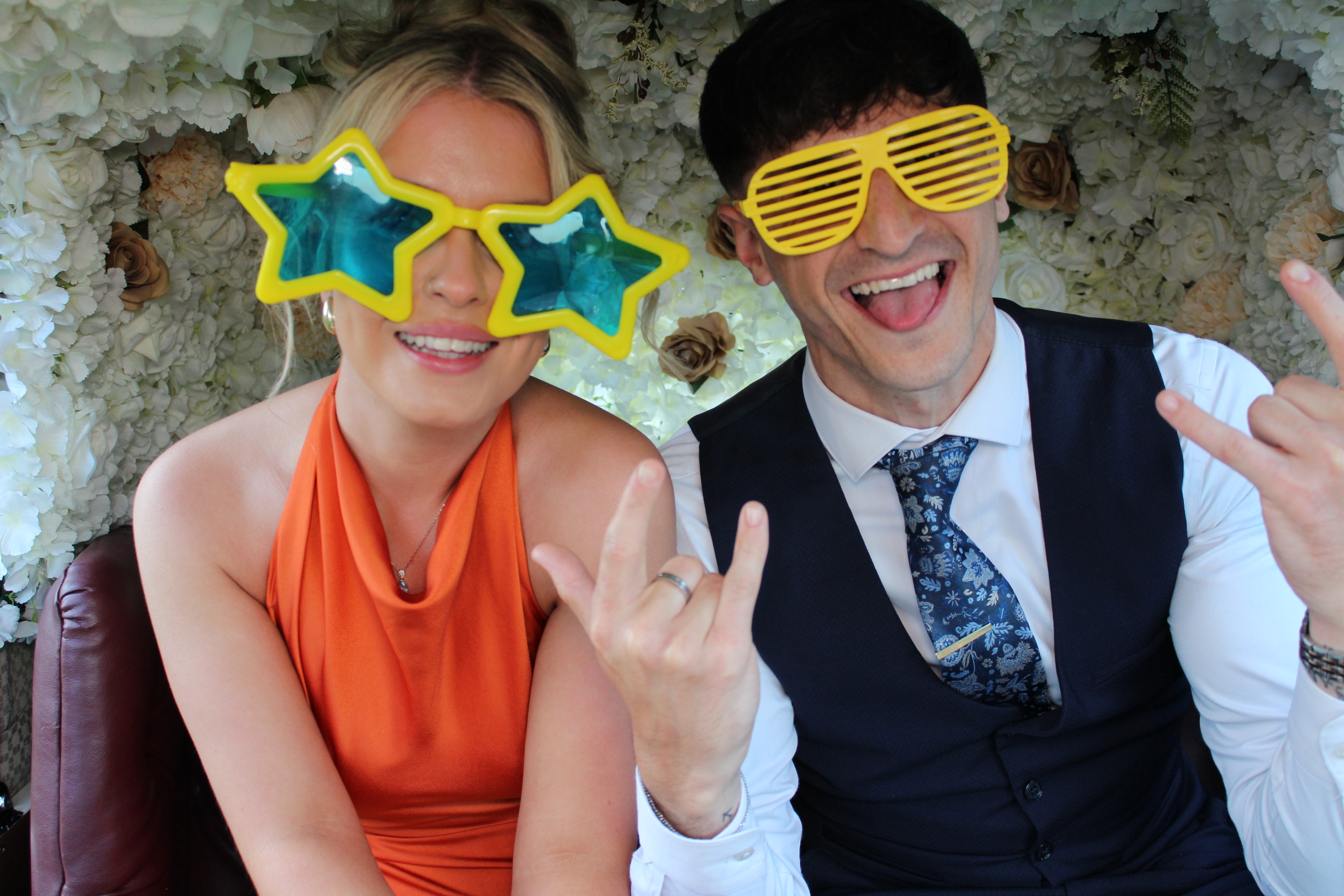 Wedding guests laughing with party props inside a colourful tuk tuk photobooth